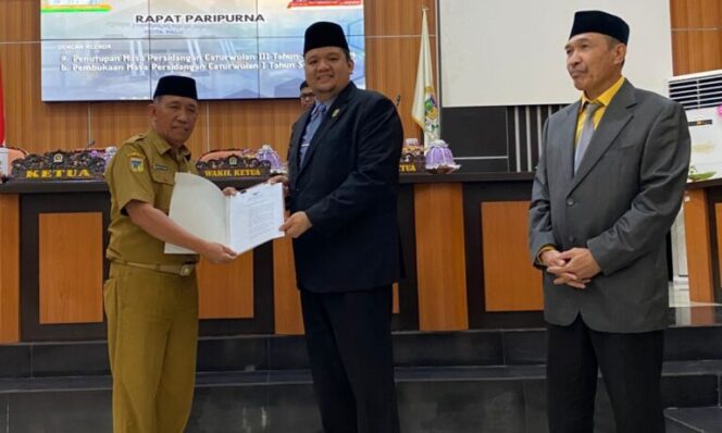 
					Ketua DPRD Kota Palu, Rico A T Djanggola, menyerahkan berita acara rapat paripurna ke Asisten Administrasi Umum Sekretariat Daerah Kota Palu, Imran, S.E., M.Si. (Foto : Istimewa)