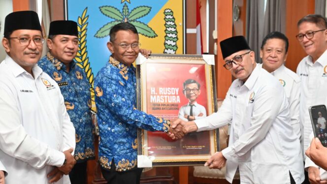 
					Ketua FKUB Sulteng, Prof. KH. Zainal Abidin, menyerahkan sebuah pigura berisi karikatur H. Rusdi Mastura sebagai bentuk penghargaan. (Foto: Humas Pemprov Sulteng)