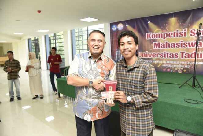 
					Rektor Universitas Tadulako Prof. Dr. Ir. Amar ST., MT., IPU., Asean Eng. Menyerahkan Piala Kepada Juara Satu Lomba Stand Up Comedy Pada Kegiatan Kompetisi Seni Mahasiswa. (Foto: Istimewa)
